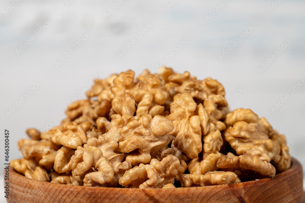 Walnut in wood bowl. Walnut peeled on white wood background. Close up Walnut in wood bowl. Walnut peeled on white wood background. Close up