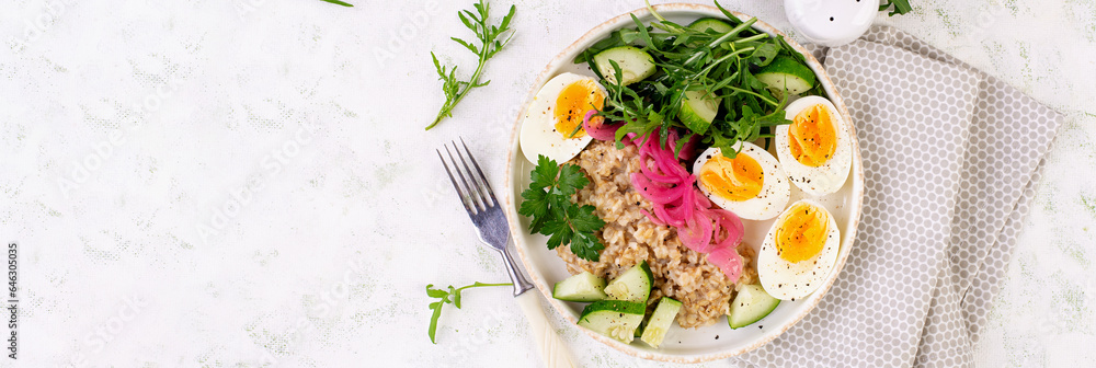 Breakfast oatmeal porridge with boiled eggs, cucumber, red onion and greens. Healthy balanced food. Top view, banner Breakfast oatmeal porridge with boiled eggs, cucumber, red onion and greens. Healthy balanced food. Top view, banner