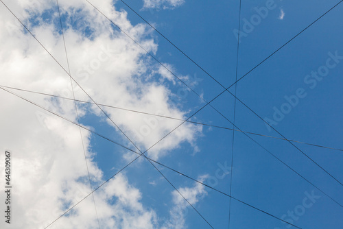 Many electrical wires against a background of blue sky with white clouds