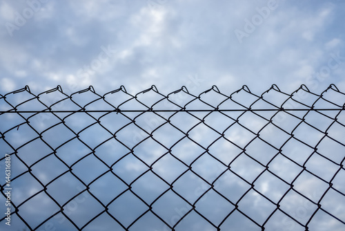 Close-up of an old barbed wire fence with a cloudy sky in the background