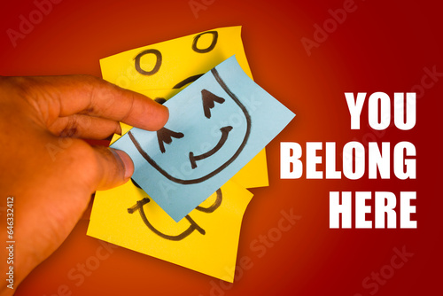 hand holding smiling yellow sticky note, symbol of belonging and inclusion. Business, inclusion and ownership concept.