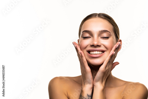 Portrait of beautiful female model touching her glowing, moisturized perfect skin on white background