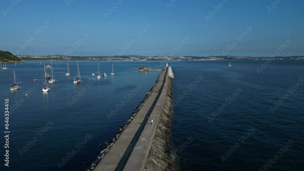 Brixham, Torbay, South Devon, England: DRONE VIEW: Brixham Harbour Lighthouse: the Outer Harbour Wall; Joggers; Anglers and walkers along the Wall. Brixham is both a fishing port and a holiday resort. Brixham, Torbay, South Devon, England: DRONE VIEW: Brixham Harbour Lighthouse: the Outer Harbour Wall; Joggers; Anglers and walkers along the Wall. Brixham is both a fishing port and a holiday resort.