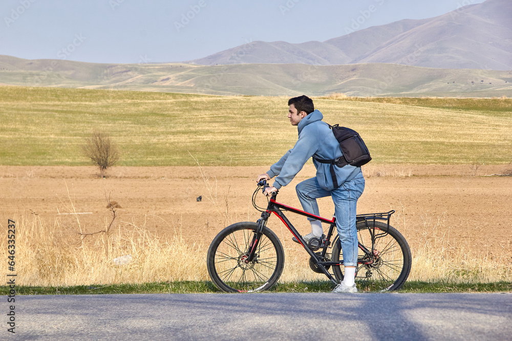 A teenage tourist with a bicycle on the background of the highlands in the fresh air