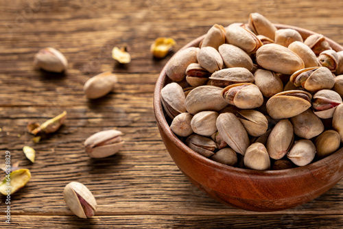 Bowl with pistachios on the old rustic wooden background. Dried nuts concept.