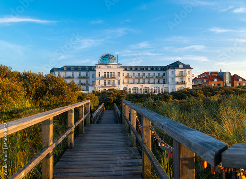 Waterfront of Juist island in Germany with historic monument and former health resort in the dunes near beach of the North sea. Wooden footbrige with colorful love locks on a sunny summer evening. photo