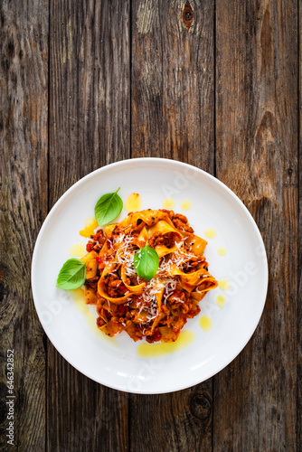 Tagliatelle con ragù alla bolognese - pasta with minced meat and tomato sauce on wooden table