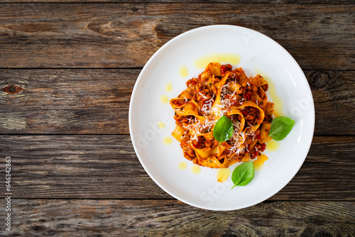 Tagliatelle con ragù alla bolognese - pasta with minced meat and tomato sauce on wooden table