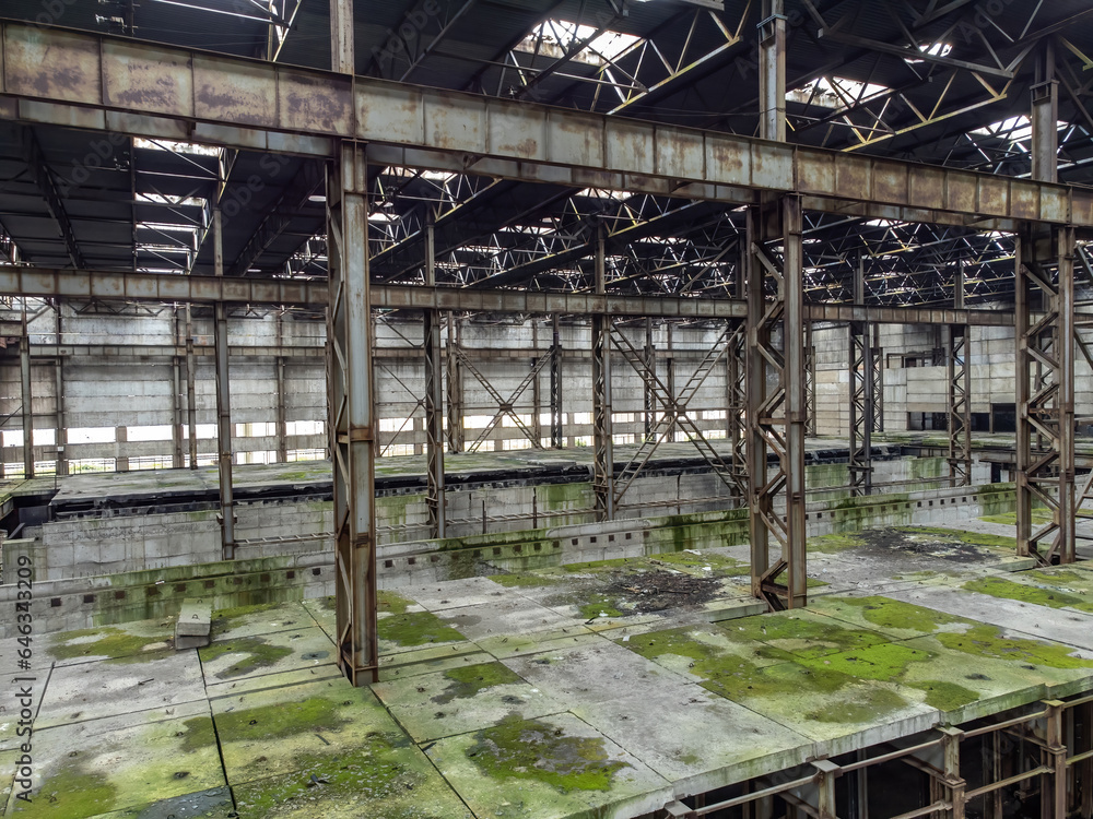 Abandoned industrial building. Metal construction with traces mold. Former factory building is abandoned. Territory of industrial enterprise. Manufactory building is damaged by mold. Abandoned plant