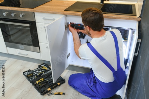 Obraz na płótnie kitchen installation. Worker assembling furniture