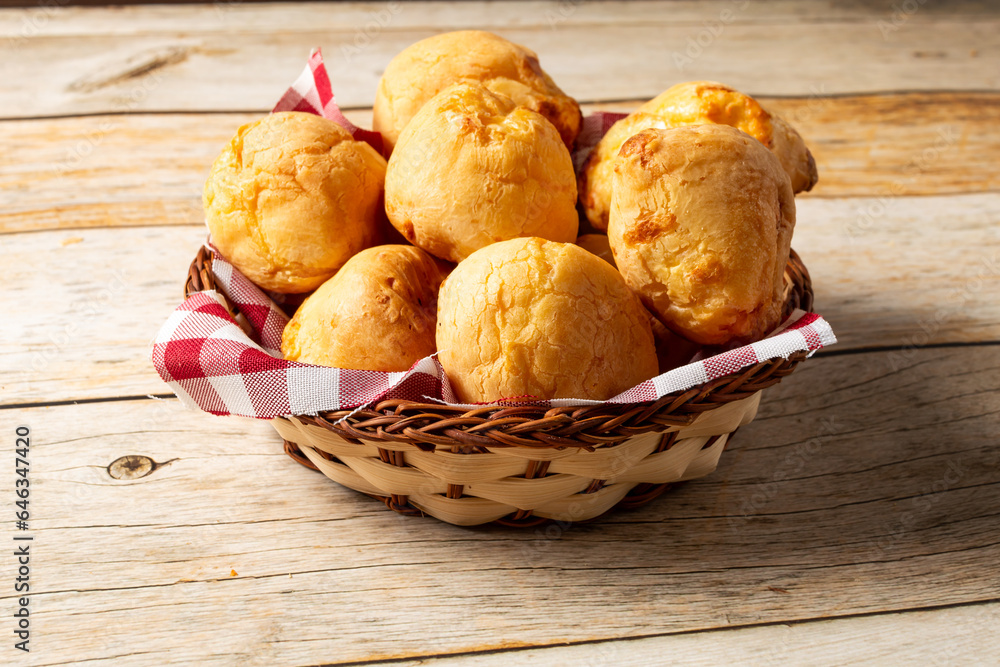 wooden basket with brazilian pão de queijo, or cheese breads in english