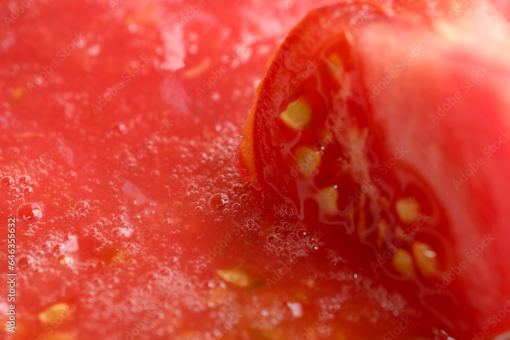 A piece of red ripe sweet tomato in a plate with tomato juice A piece of red ripe sweet tomato in a plate with tomato juice