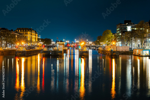 Illuminated Canals and Riverside Delights: Exploring Amsterdam After Dark. Captivating Cityscape of Amsterdam at Night: A Delightful Blend of Tradition and Modernity