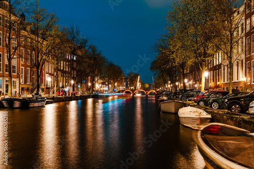 Illuminated Canals and Riverside Delights: Exploring Amsterdam After Dark. Captivating Cityscape of Amsterdam at Night: A Delightful Blend of Tradition and Modernity © Ilja