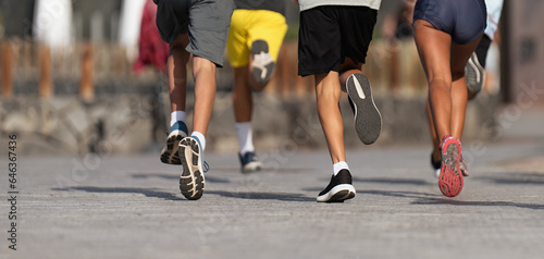 Fototapeta Naklejka Na Ścianę i Meble -  Running children, young athletes run in a kids run race, running on city road detail on legs, running in the light of morning