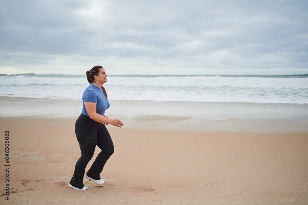 Motivated body positive sports woman jogging at the sandy sea beach Motivated body positive sports woman jogging at the sandy sea beach