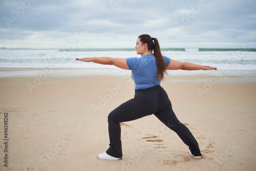 Caucasian plus size woman looking away while warming up at the sea beach