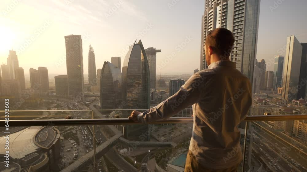 Young Man Succeed In High Rise Apartment Looking at Urban Buildings Young Man Succeed In High Rise Apartment Looking at Urban Buildings