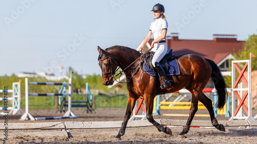 Young rider woman riding horse warming up before showjumping competition