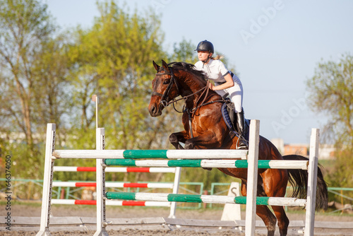 Young horseriding woman jumping over the obstacle on her showjumping course