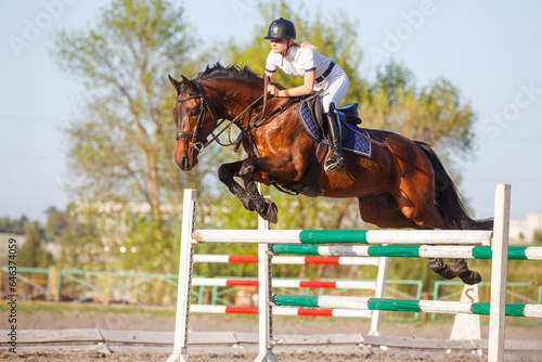 Young horseriding woman jumping over the obstacle on her showjumping course © skumer