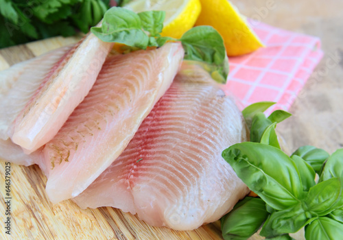 fresh raw tilapia fish fillet on wooden board