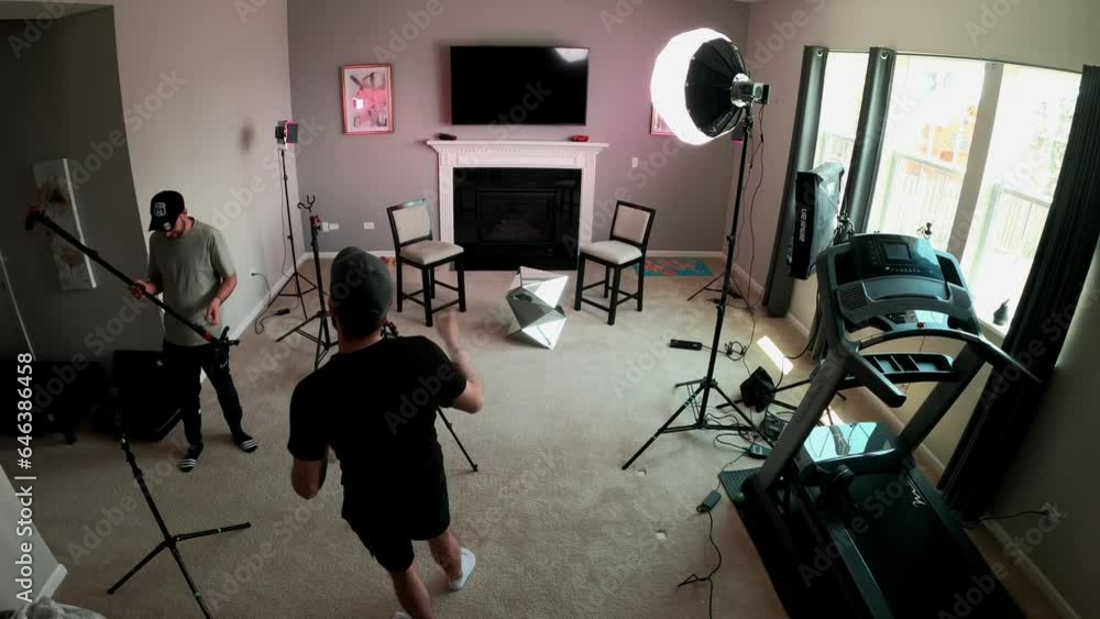 Two caucasians videographers setting up camera equipment indoor for a ...