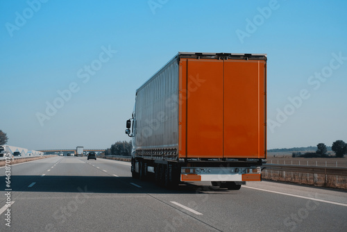 Modern semi-trailer trucks on the highway driving in the right lane. Commercial vehicle for shipping and post delivery. Shipping of the goods on land door-to-door