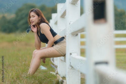 A beautiful Asian woman sitting on a white fence.