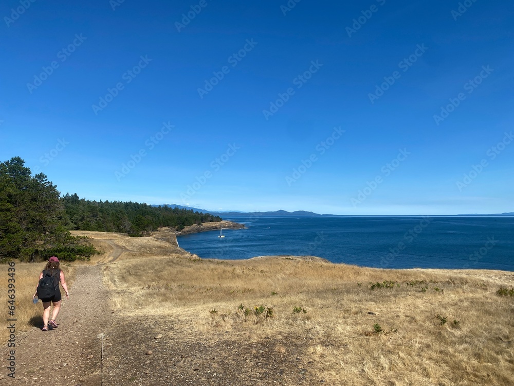 A young woman hiking along a beautiful coastline trail on Hornby Island. A young woman hiking along a beautiful coastline trail on Hornby Island.