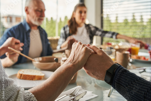 Canvas Print Christian family praying before breakfast and holding hands at the kitchen table