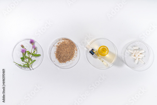 Milk Thistle supplies, powder and oil. Silybum marianum, natural organic wild flower superfood product - whole and grain seeds, pills, oil with fresh thistle flowers