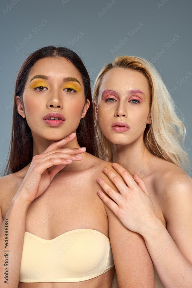 diverse models with vibrant eye makeup looking at camera on blue backdrop, beauty trend concept diverse models with vibrant eye makeup looking at camera on blue backdrop, beauty trend concept
