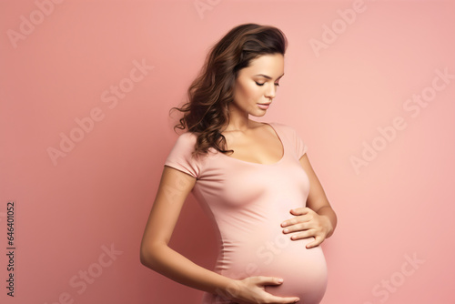 A beautiful pregnant woman in pink, with her eyes closed, on a pink background 