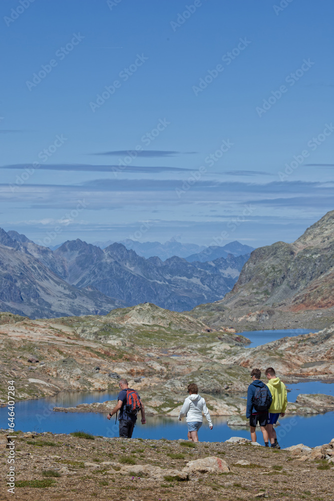OZ-EN-OISANS, FRANCE, August 8, 2023 : Hikers walk on paths over the lakes of Grandes Rousses mountain range