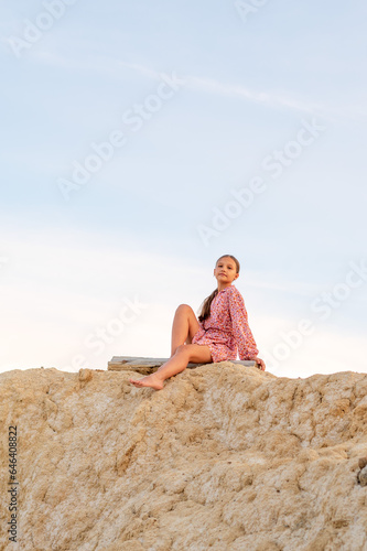 A girl sits on the edge of a cliff looking at the beauty of nature.