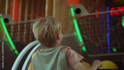 A boy throws a basketball into a basket at an amusement park