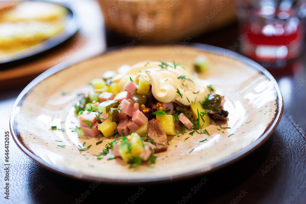 Delicious potato salad with slices of ham and mushrooms close up