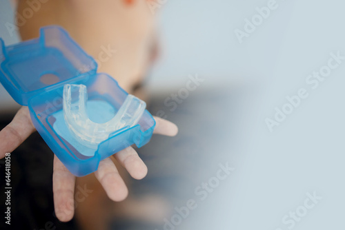 transparent mouth guard made of silicone, for straightening teeth in children, in a girl\'s hand, in daylight. Hygiene, dental care, occlusion correction, new technologies