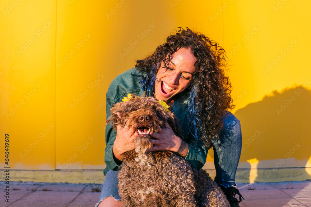 Happy woman playing with water dog in front of yellow wall Happy woman playing with water dog in front of yellow wall