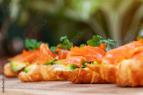 Smoked salmon with cream cheese and avocado slide on fresh croissants.