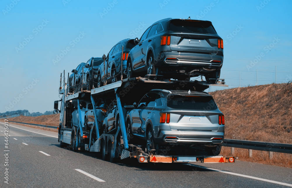 Car carrier trailer truck with brand new SUV cars for sale. New car delivery and shipping. Car transporter trailer loaded with many new cars for the customers. Two level modular hydraulic semi trailer