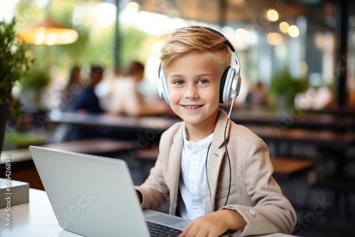A Boy blonde student smile online learning using laptop and headset