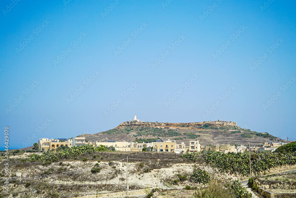 A landscape view of a lighthouse on top of the cliff in Gozo, Malta