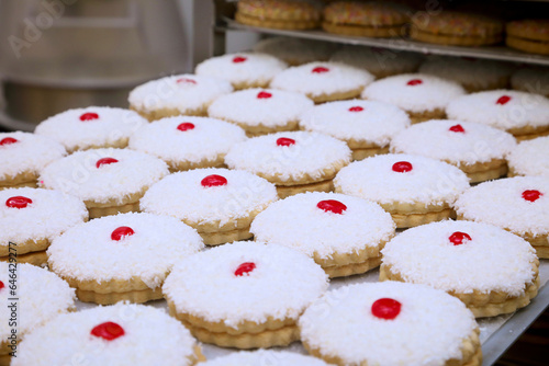 tray full of cakes with coconut topping and cherry