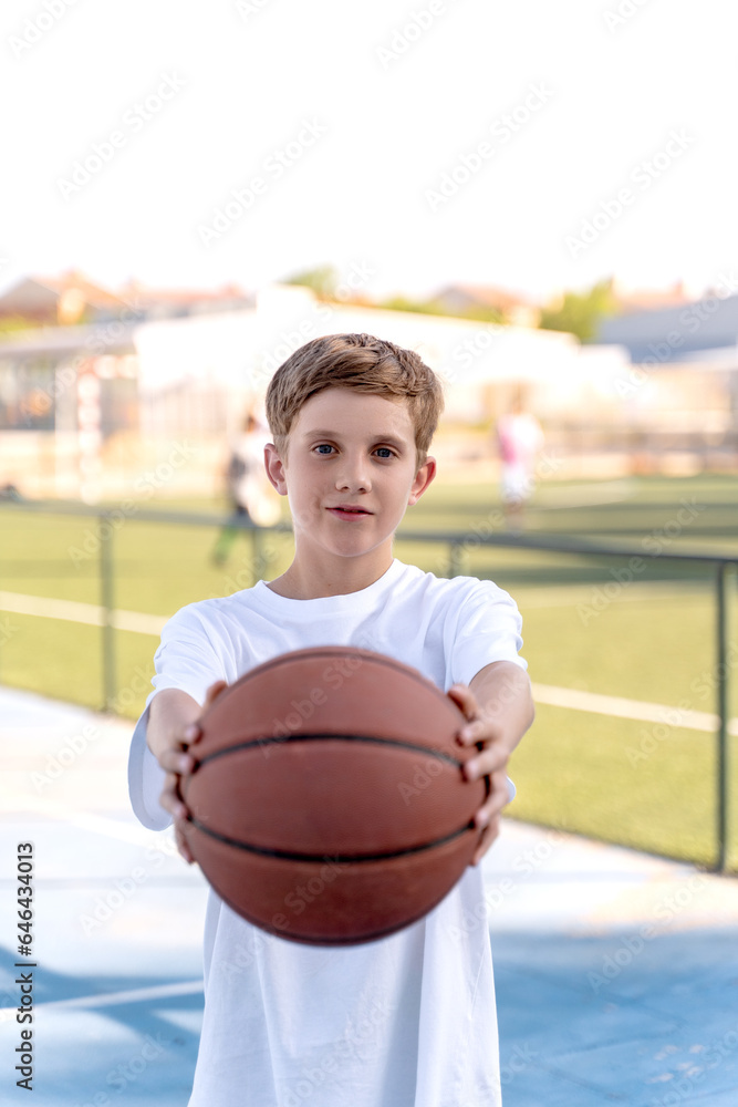 Portrait of a young boy posing with a basketball ball outdoors. Sports concept. Portrait of a young boy posing with a basketball ball outdoors. Sports concept.