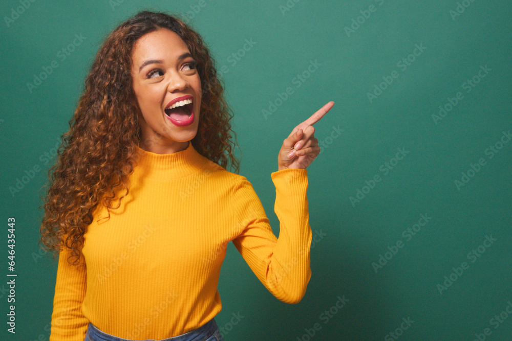 Beautiful young woman points to copy space right, excited, sale, green studio Beautiful young woman points to copy space right, excited, sale, green studio