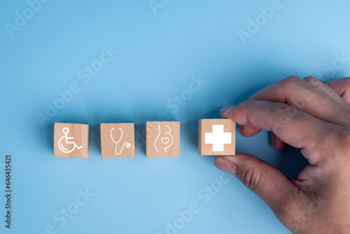 Arranging wooden block cubes into the shape of a healthcare medical icon, symbolizing insurance for your health and Plus Sign Concept.