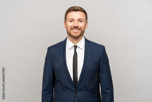 Smiling confident businessman looking at camera. Entrepreneur investor man in suit isolated on gray studio background with copy space for advertising. Investments, business development trading concept