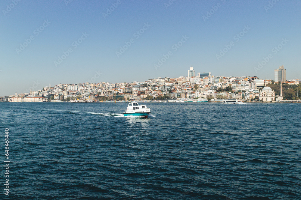 View of bosphorus strait water at midday with blue waters and beautiful skyline at horizon and small boat passing by